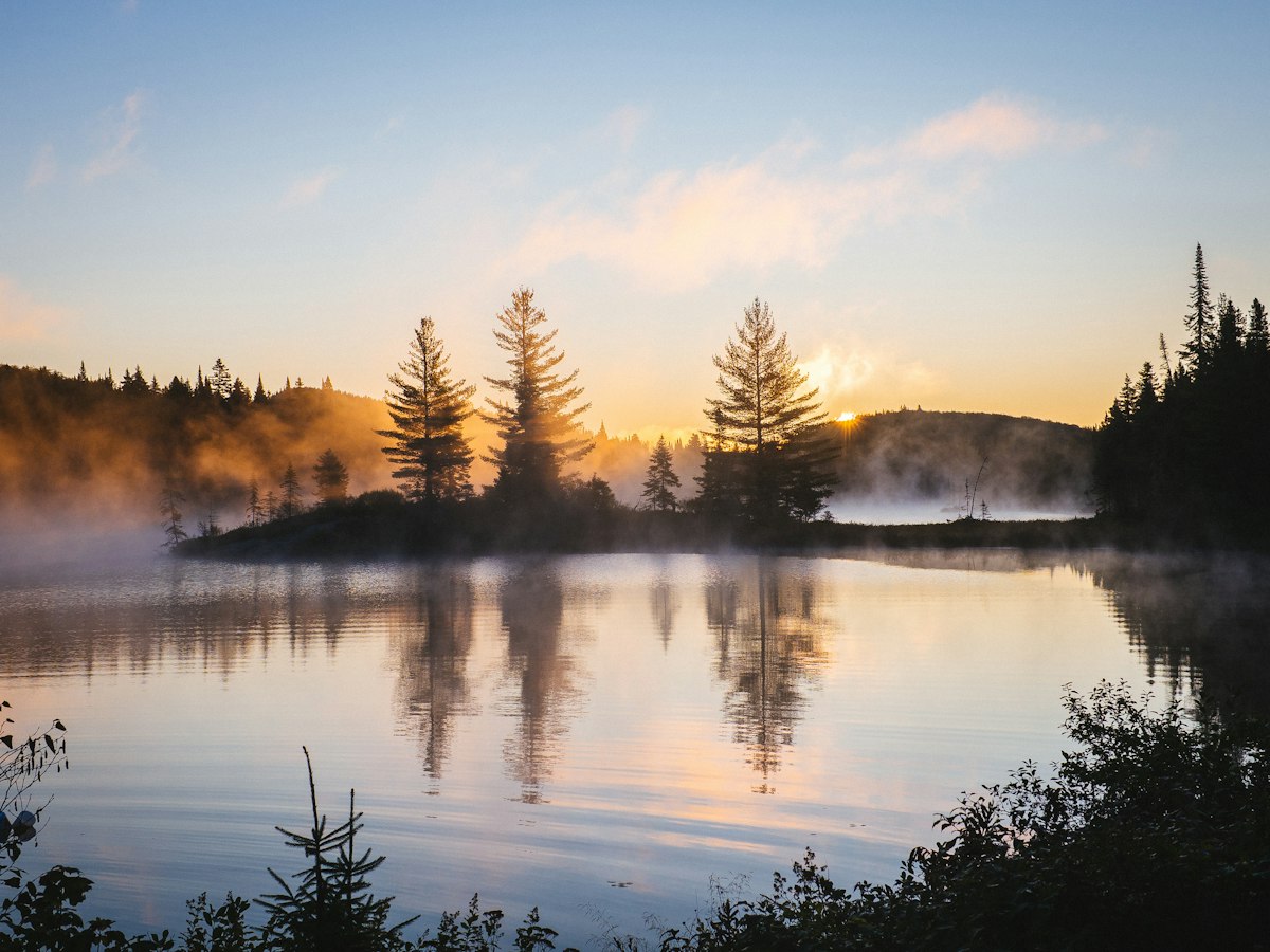 Ruhiger See im Morgennebel bei Sonnenaufgang